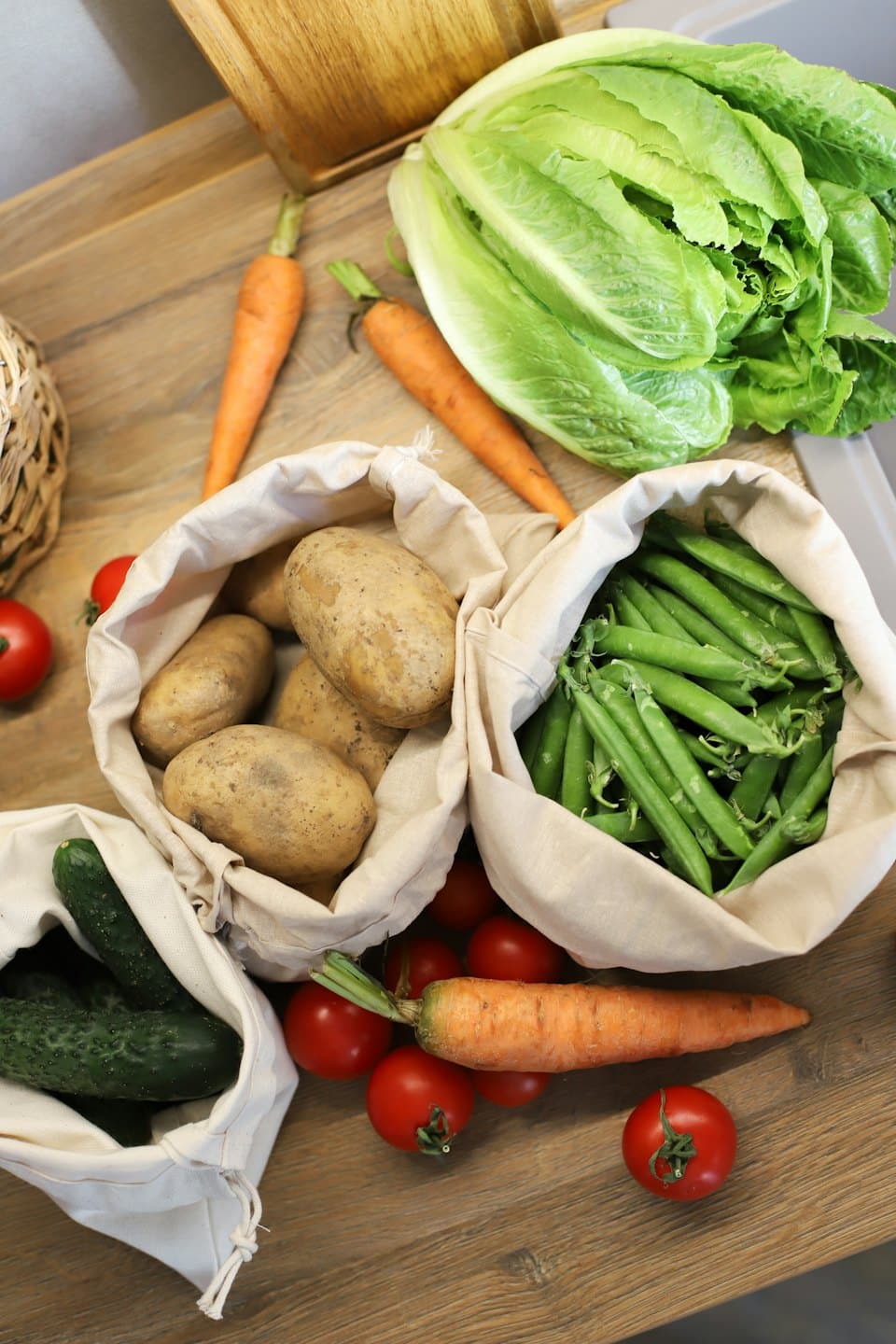 Fresh vegetables are arranged on a wooden kitchen surface.