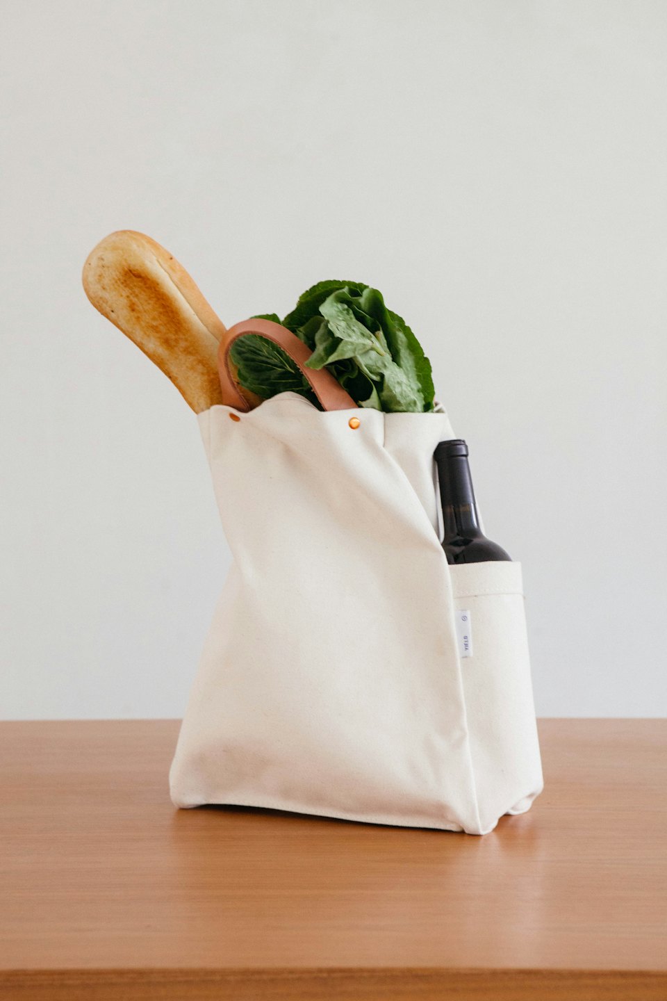 Tote bag full of groceries on a wooden surface.