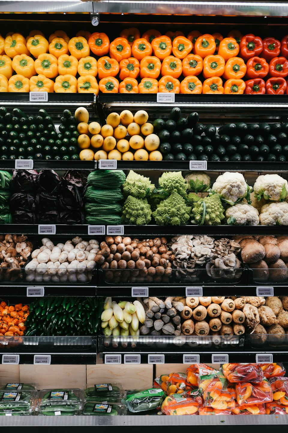 Grocery store produce aisle with colorful fruits and vegetables.