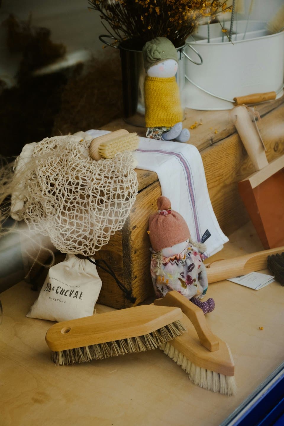 Eco-friendly household items and fabric dolls displayed on a wooden table.