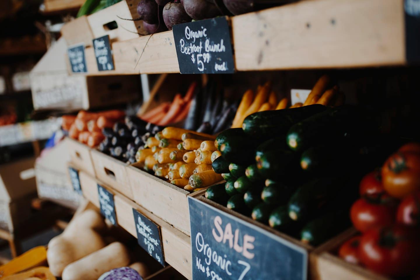 Fresh organic vegetables in rustic wooden crates on shelves.